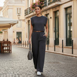 Woman in a black outfit walking on a cobbled street in an urban setting