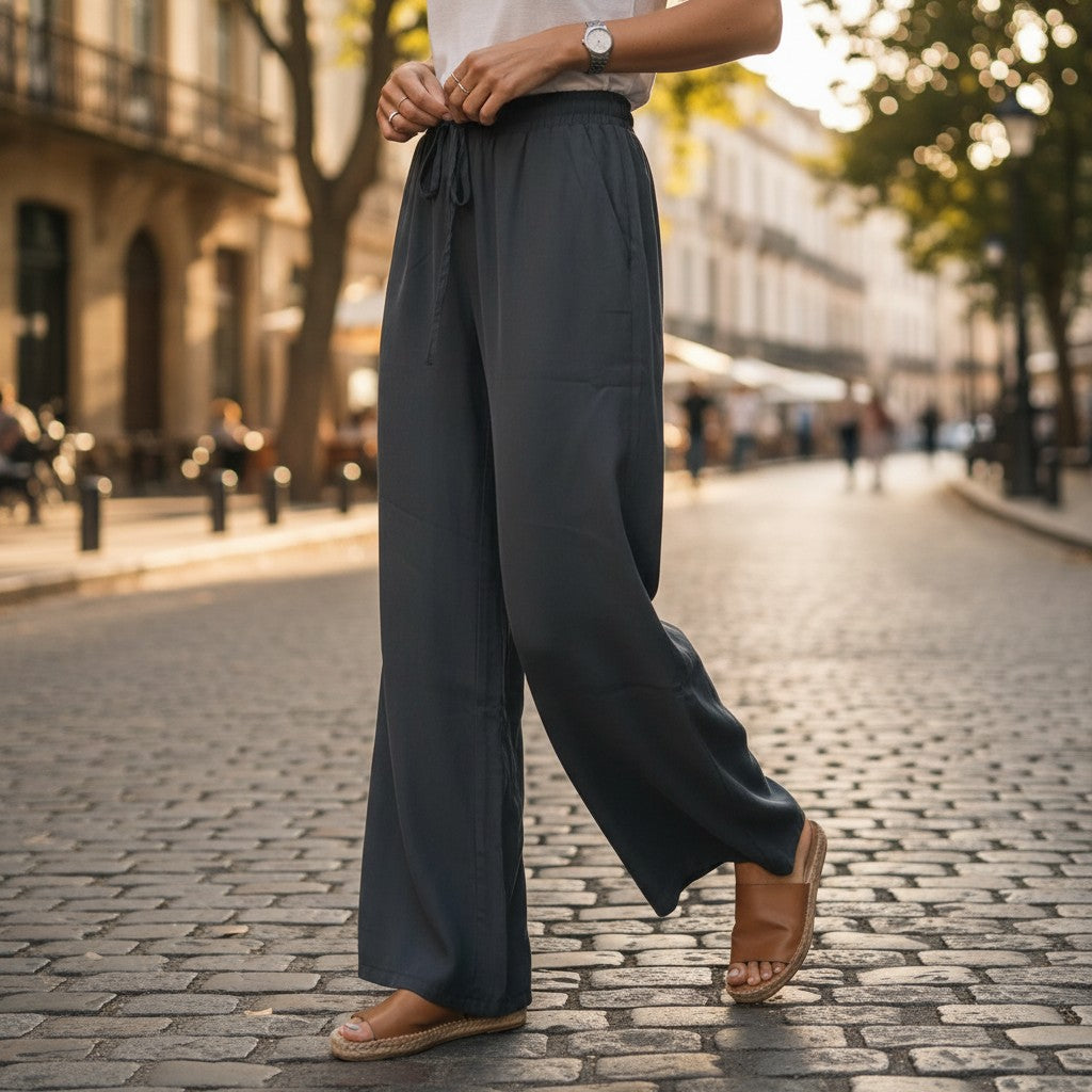 Person wearing dark gray wide-leg pants on a city street.