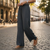 Person wearing dark gray wide-leg pants on a city street.