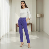 Woman wearing a white top and dark purple pants in a minimalistic room