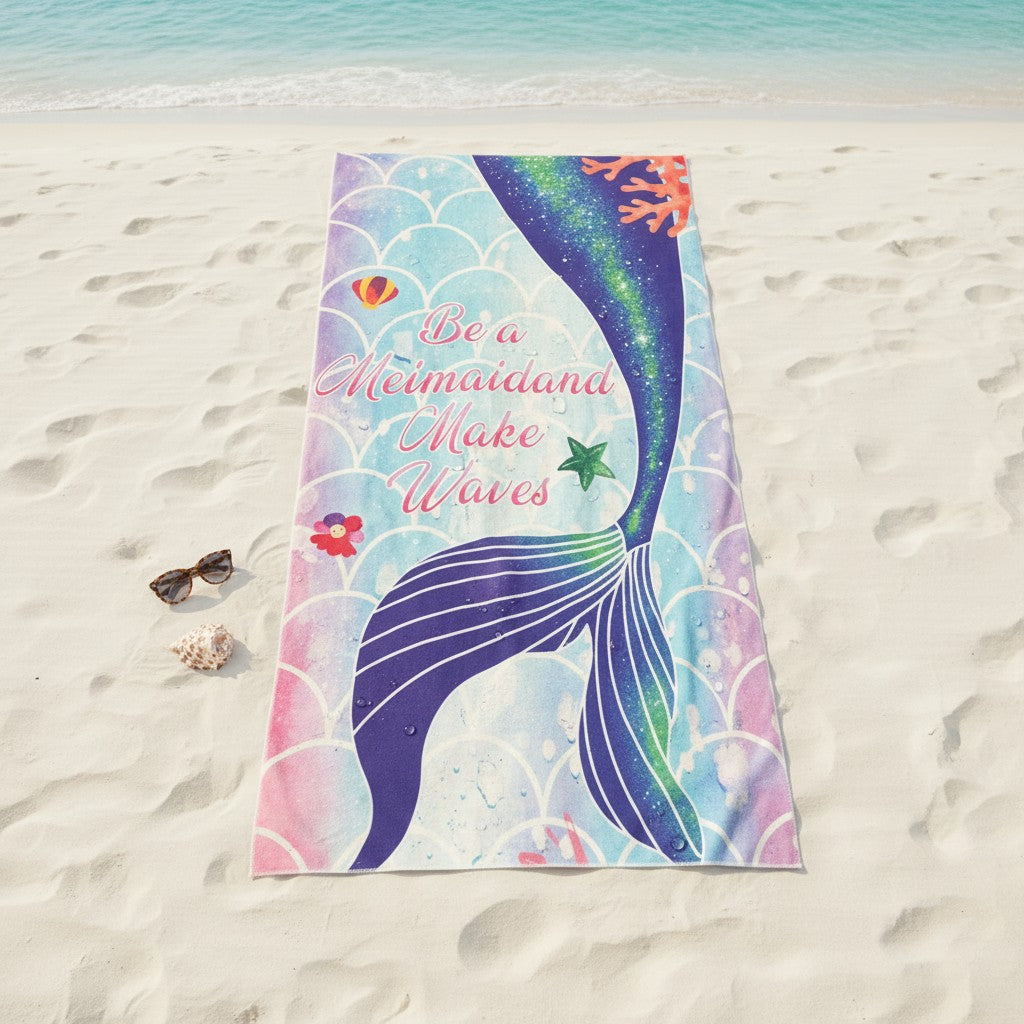 Colorful mermaid-themed towel on a sandy beach with sunglasses and shells.