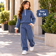 Girl walking in a denim blue half zip jogging set with white piping, ruffle cuffs and white sneakers