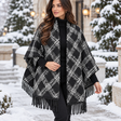 Black and white diamond plaid blanket wrap draped over the shoulders with long black fringe in the snow
