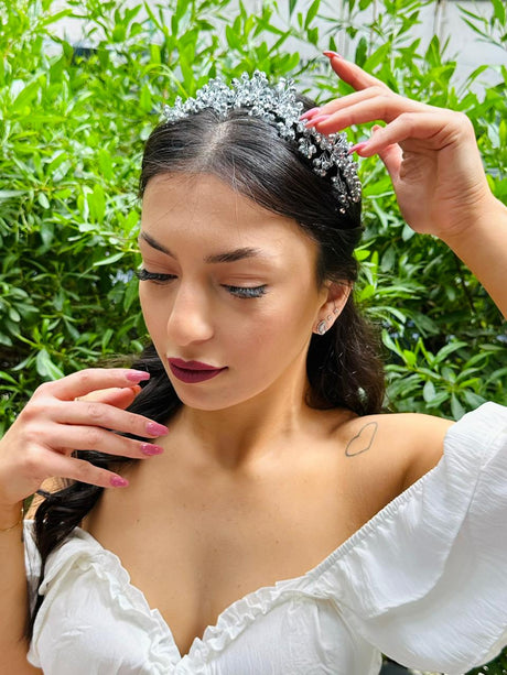 Woman wearing a diamond tiara with green foliage in the background
