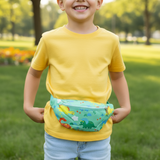 Boy in a yellow tee holding a mint green dinosaur print bum bag around his waist
