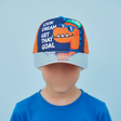 Boy wearing an orange and navy dino kids cap with a cartoon dinosaur in sunglasses