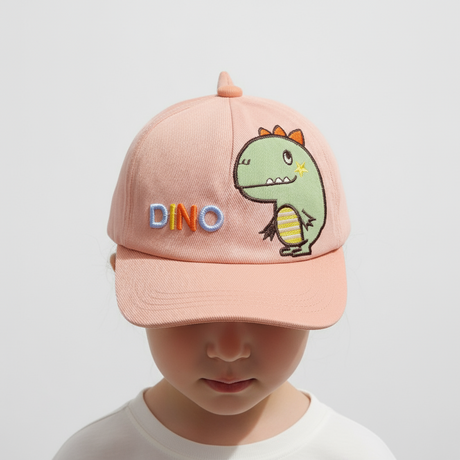 Child wearing a peach corduroy baseball cap with an embroidered green dinosaur patch and DINO lettering