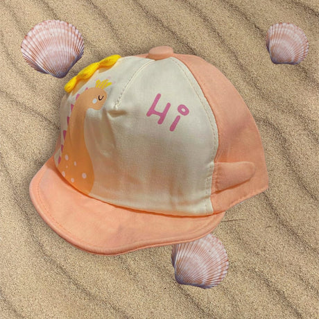 Salmon and cream kids sun cap with a printed dinosaur, yellow spikes and pink Hi text, laid flat on sand
