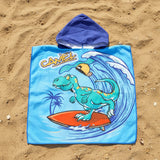 Sky blue dinosaur poncho towel with a teal surfing dino and indigo hood flat lay