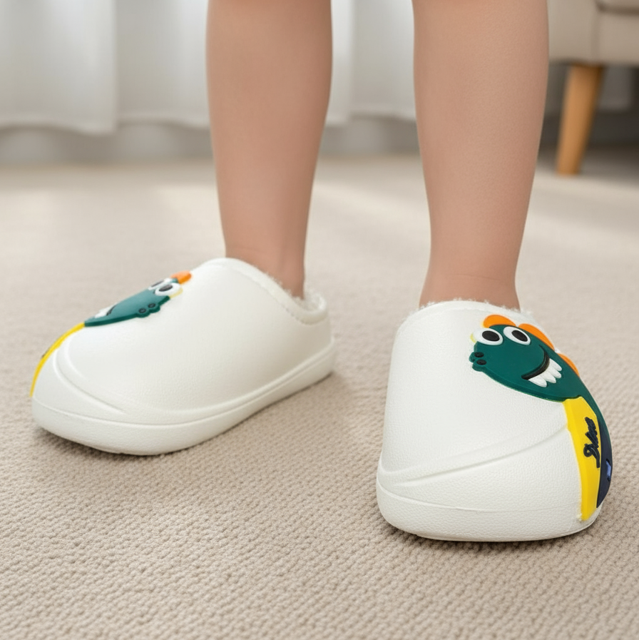 Close up of white slip on slippers with a green cartoon dinosaur worn on carpet