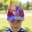 Purple and red kids baseball cap with a red haired cartoon princess print, worn by a child outdoors
