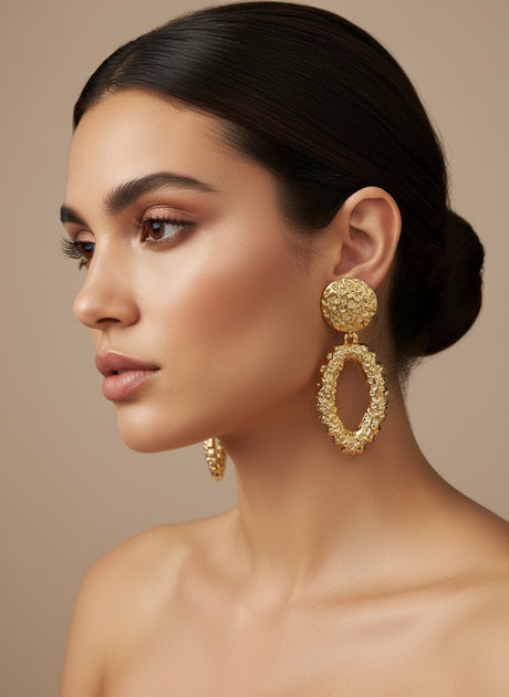 Woman wearing gold earrings against a beige background