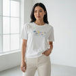 Woman wearing a white tshirt with colorful text in a bright room
