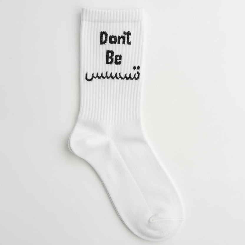 White ribbed crew sock with a Don't Be slogan in black English and Arabic lettering