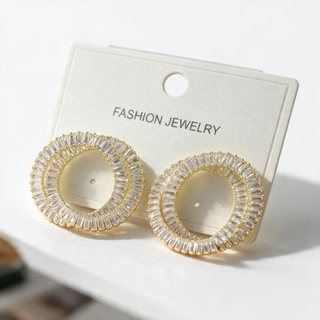 Gold double ring earrings lined with clear baguette crystals on a white card