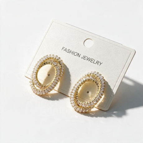 Gold double oval earrings lined with clear baguette stones on a white card