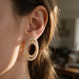 Gold double oval earring with clear baguette crystals in warm sunlight