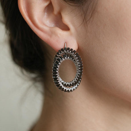 Black and silver tone double oval baguette crystal earring worn on the ear