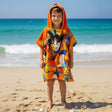 Boy wearing an orange Dragon Ball hooded poncho towel with the hood up on the beach