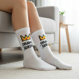 Person wearing White socks with 'Drama Queen' text sitting on a couch in a cozy living room