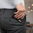 Person wearing grey pants and a checkered shirt, holding a black wallet