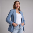 Dusty blue shawl collar blazer worn open over a white top, hands in jean pockets