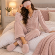 Woman in a dusty pink ribbed velour pyjama shirt and trousers with eye mask and slippers