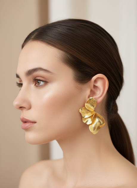 Woman wearing gold earrings with a neutral background