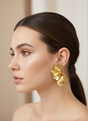 Woman wearing gold earrings with a neutral background