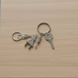 Electrician keychain with light bulb, plug, and screwdriver charms on light wood