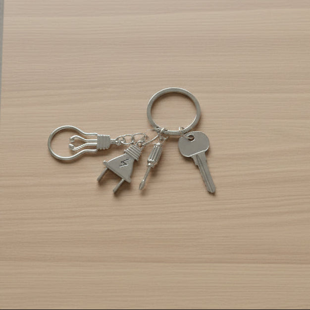 Electrician keychain with light bulb, plug, and screwdriver charms on light wood