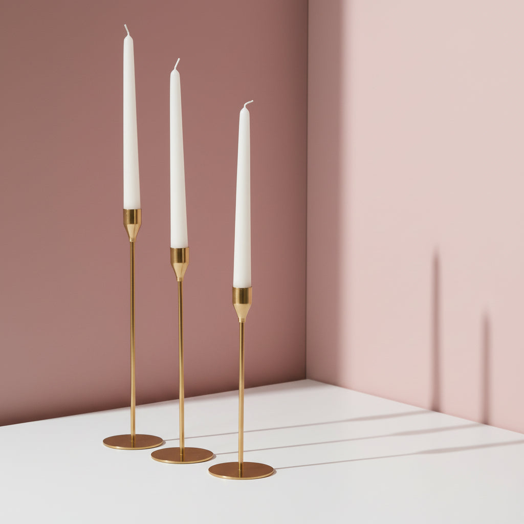 Three all gold holders stepping down in height with slim unlit white tapers