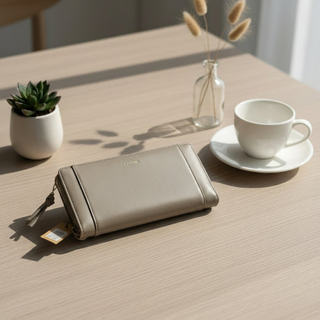 Grey wallet on a wooden table with a cup, a vase, and a plant