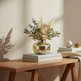 Mercury gold finish vase raised on two books, holding olive branches and dried filler