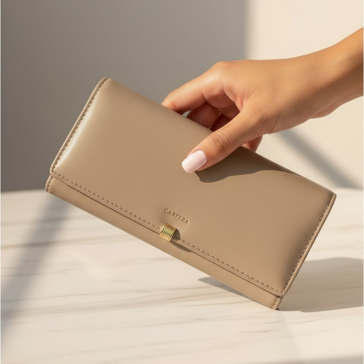 Beige wallet held by a hand on a light background