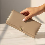 Beige wallet held by a hand on a light background