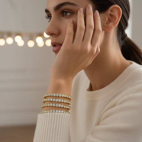 Woman wearing a cream sweater with decorative bracelets, holding her hand near her face