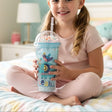 Girl sitting on a bed holding an ice blue elephant print cup with a bead dome lid