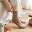 Tan ribbed sock with a white bow motif, worn with a linen skirt and loafers