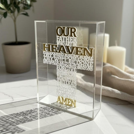 The English prayer raised in white on a clear block, its shadow cast across marble