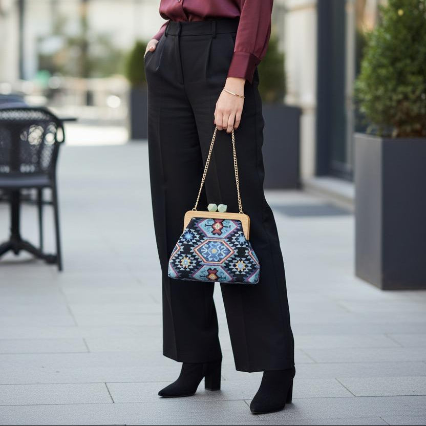 Ethnic pattern handbag carried with black wide leg trousers on a city pavement