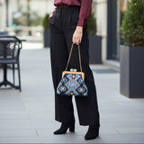 Ethnic pattern handbag carried with black wide leg trousers on a city pavement