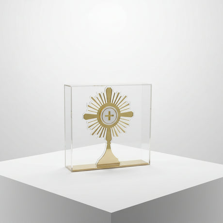 Rayed gold monstrance with a frosted host disc standing in a clear acrylic case