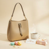 Beige pebbled handbag with a short top handle, styled with coffee and macarons