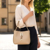 Beige handbag held at the shoulder with a white blouse and navy trousers