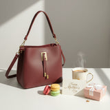 Burgundy pebbled handbag beside a gold rimmed mug, macarons and a pink Mother's Day gift box
