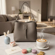 Grey pebbled handbag on a living room table with coffee, macarons and a card for mum