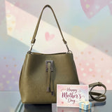 Olive handbag shown with its detachable shoulder strap laid out beside it