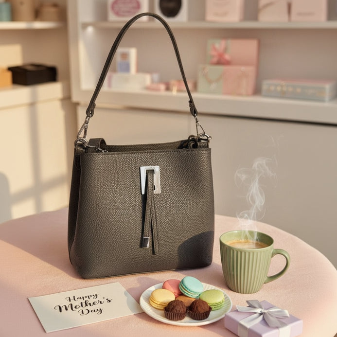 Dark grey pebbled handbag with silver hardware on a pink table in a boutique setting