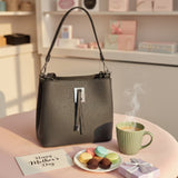 Dark grey pebbled handbag with silver hardware on a pink table in a boutique setting